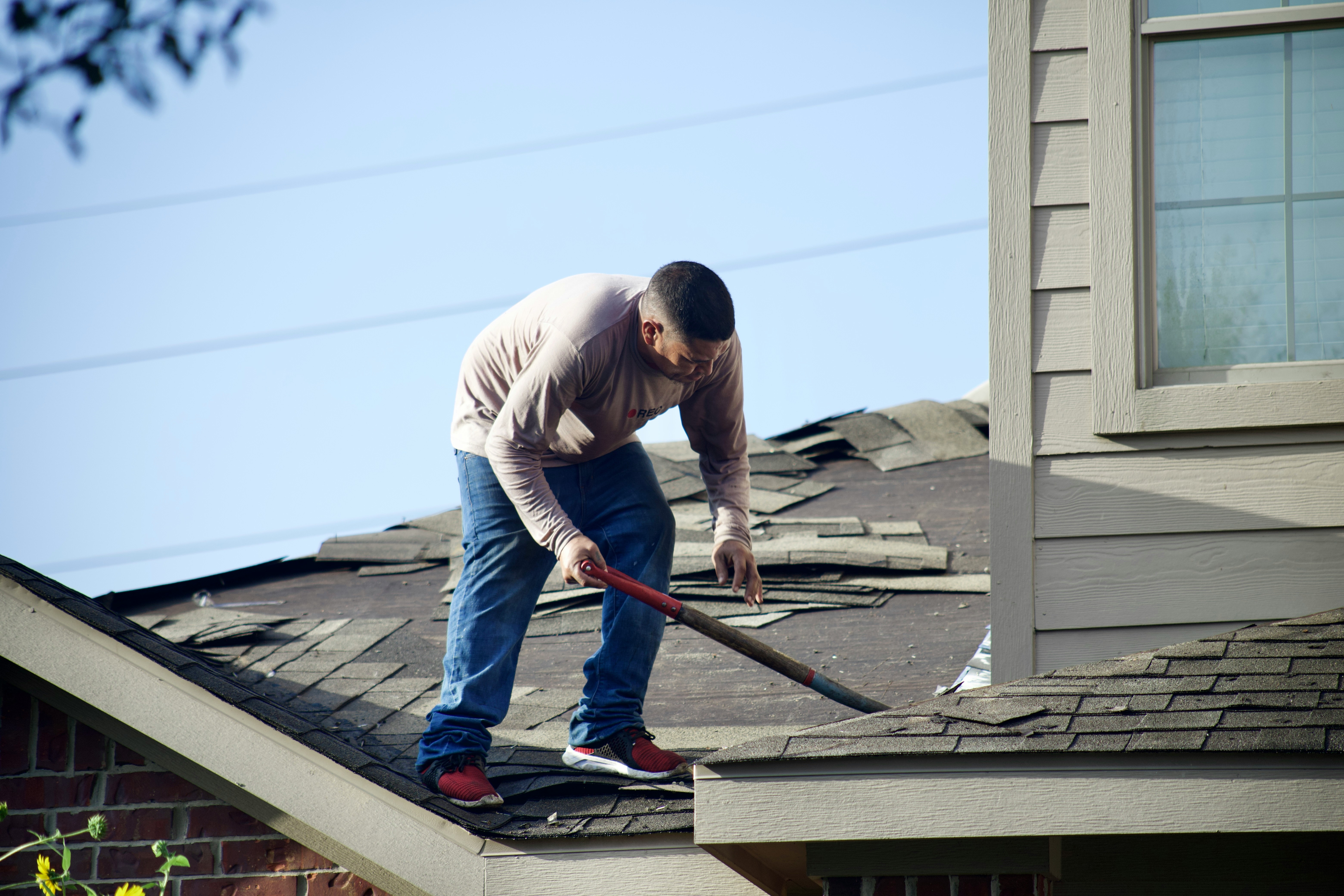 Worker removing roof shingles during renovation